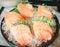 Sashimi consists of raw salmon fish slice placed on the ice in a black ceramic cup in a restaurant