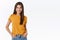 Sassy good-looking feminine brunette woman in yellow t-shirt, hold hands in jeans pockets, smiling self-assured with