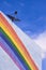 Satellite dish on top of white building with rainbow stripes on building wall against blue sky