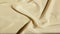 Satin beige fabric background. Wavy silk fabric. Slow motion of fabric