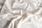 Satin crumpled fabric of light milky color, top view. Natural bed linen, sheets, abstract background of luxury fabric