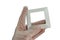 Satin white design plastic light switch frame held in left hand in transparent latex safety glove, white background