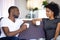 Satisfied African American couple talking, drinking coffee at home