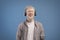 Satisfied calm albino guy in headphones enjoying favorite music with closed eyes standing over blue background