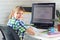 A satisfied child sits at a computer table and looks into the frame