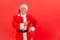 Satisfied elderly man with gray beard wearing santa claus costume standing with hand on hips