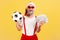 Satisfied elderly man in santa claus hat and stylish sunglasses holding soccer ball and dollar banknotes, sports betting, big win