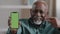Satisfied elderly man showing green screen on smartphone happy pensioner advertise application service website african
