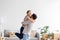 Satisfied european young husband lifts and hugs his wife in room interior have fun together