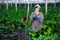 Satisfied female farmer demonstrates ripe zucchini in greenhouse