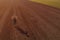 Satisfied female farmer standing in ploughed field and looking into distance, drone photography