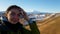 A satisfied girl traveler takes a selfie against the background of the bright mount Elbrus. Brunette`s trip to the Caucasus