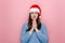 Satisfied good looking female in Christmas red hat keeps palms in praying gesture, has positive expression, gentle smile