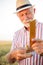 Satisfied gray haired senior agronomist or farmer measuring wheat beads before the harvest