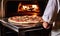 With a satisfied grin, the man retrieves the perfectly baked pizza from the hot oven