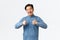 Satisfied happy asian man with braces, showing thumbs-up in approval, like and recommend product or service