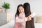 Satisfied happy chinese teenage girl hugging young lady on bed in bedroom interior, free space