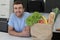 Satisfied looking man with groceries over kitchen counter