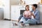 Satisfied millennial caucasian male and female with cups, drink coffee, sitting on floor