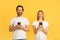 Satisfied millennial caucasian male and female in white t-shirts typing on smartphones