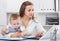 Satisfied mother with child is productively working behind laptop