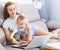 Satisfied mother with child is productively working behind laptop