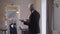 Satisfied proud senior man with grey hair in wedding blazer gesturing posing in slow motion in front of mirror indoors