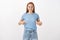 Satisfied redhead woman happy lose weight for bikini season standing in casual blue t-shirt pointing at belly or chest