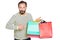 satisfied shopaholic man pointing at his colored purchases in paper bags