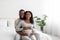 Satisfied smiling handsome millennial african american guy hugs pregnant lady with belly, sit on bed