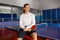 Satisfied sportsman having rest after training sitting on tennis table