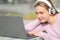 Satisfied teen with headphones checking laptop