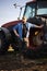 Satisfied tractor driver after work on agricultural field stands next to tractor