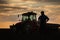 Satisfied tractor driver after work on agricultural field stands next to tractor