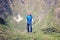 Satisfied traveler climbs the green slope, in a mountain gorge