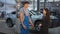 Satisfied woman shaking hands with man standing at automobile in service station. Side view happy smiling Caucasian