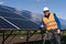 Satisfied worker showing thumb up gesture while standing near solar panels at power plant.