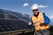 Satisfied worker showing thumbs up gesture while standing near solar panels at power plant.