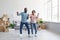 Satisfied young afro american couple dancing in flat with cardboard boxes in home interior, free space