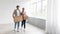 Satisfied young caucasian male and female in casual carry boxes in empty room, packing belongings, panorama