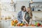 Satisfied young european male with stubble hugs female, prepares food at table with organic vegetables in kitchen