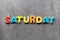 Saturday word written with colorful letters on granite stone background