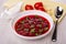 Saucebot with sour cream, tomatoes, garlic on napkin, plate with borsch, spoon on table