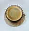 Saucer and cup of tempered brown glass with black coffee stand on a white wooden table