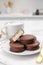 Saucer with delicious choco pies and cup of drink on white table in kitchen