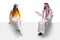 Saudi arab man sitting on a blank panel and talking to a young casual female