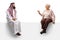 Saudi arab man in a traditional thobe sitting on a blank panel and having a conversation with an elderly woman