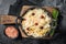 Sauerkraut in a skillet with black pepper and cranberry, Fermented cabbage. Black background. Top view