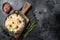 Sauerkraut in a skillet with black pepper and cranberry, Fermented cabbage. Black background. Top view. Copy space