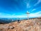 Sauofen - A woman with hiking backpack standing under a wooden cross on top of Sauofen in Austrian Alps. A vast, golden pasture